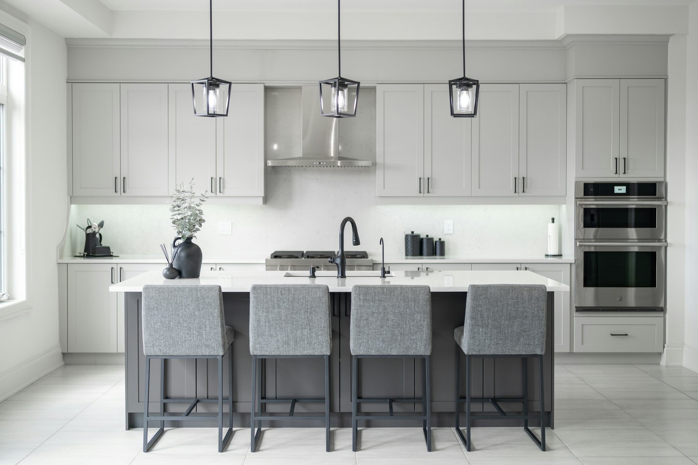 A spacious kitchen with white cabinets, an island and pendant lighting